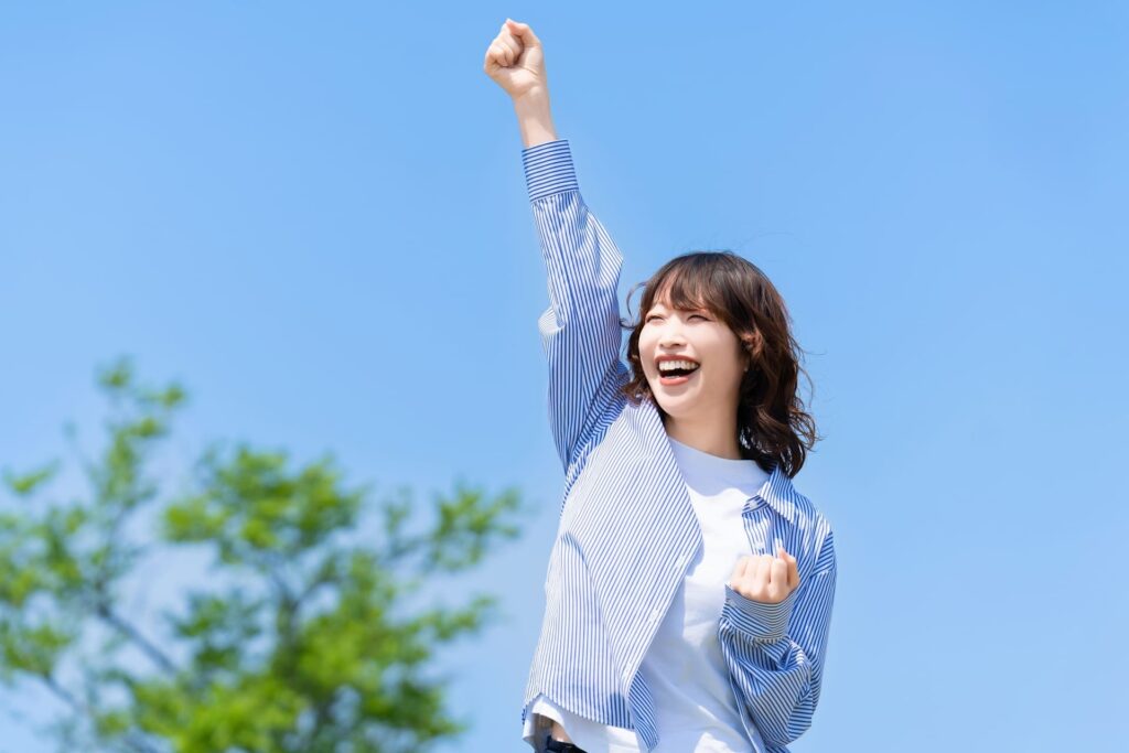 青空の下でガッツポーズする女性