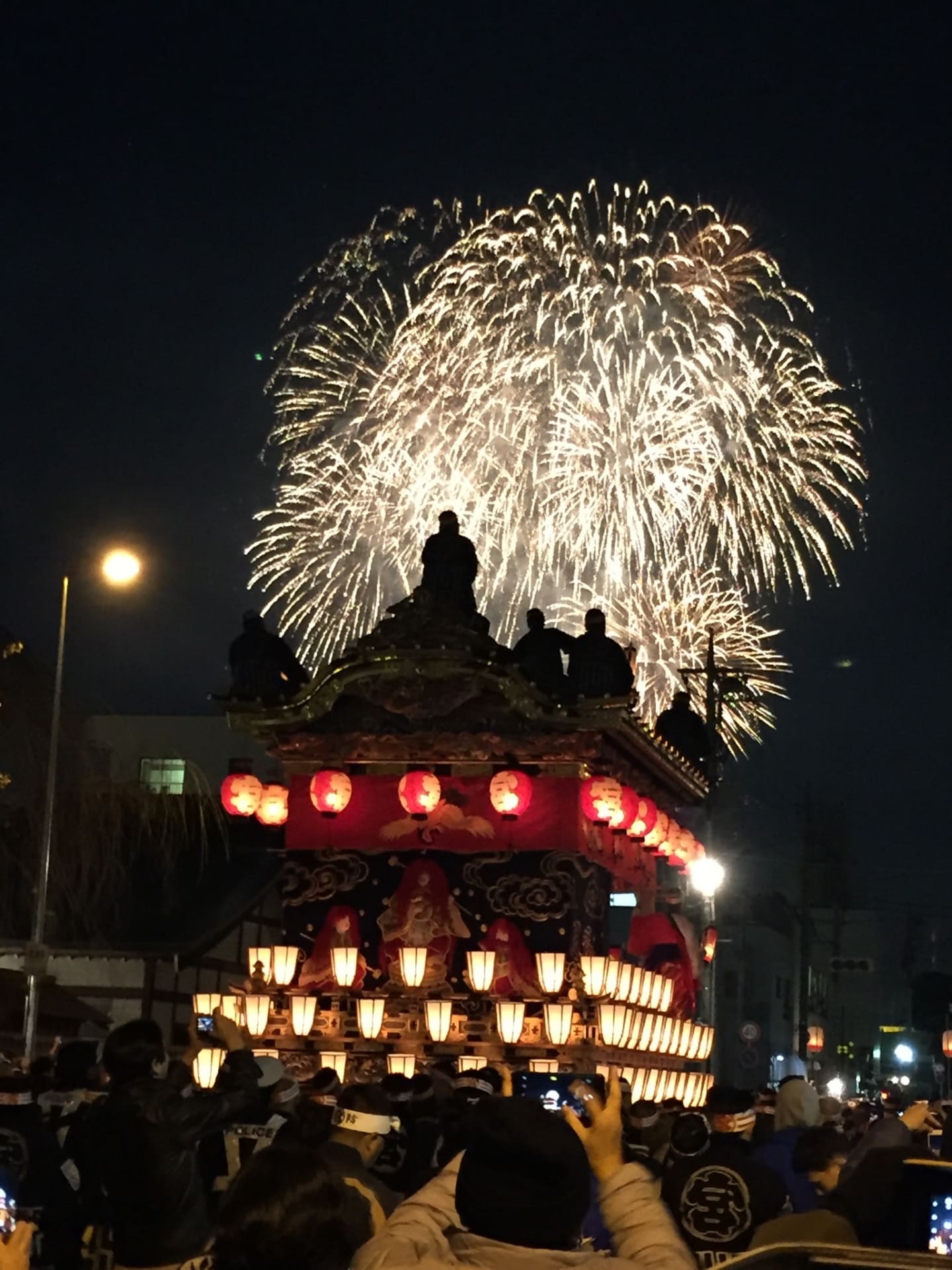 秩父夜祭の花火をバックに山車を引いている様子を夜に撮った写真